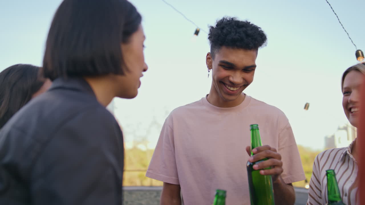 Talking youngsters celebrating weekends terrace closeup. Friends drinking beer