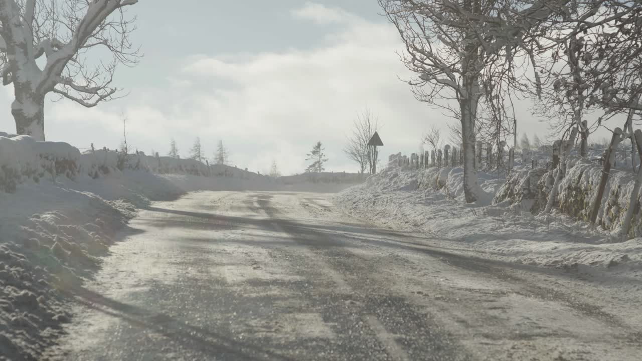 한겨울 시골의 맑은 길을 가로질러 바람이 눈을 불고 있다