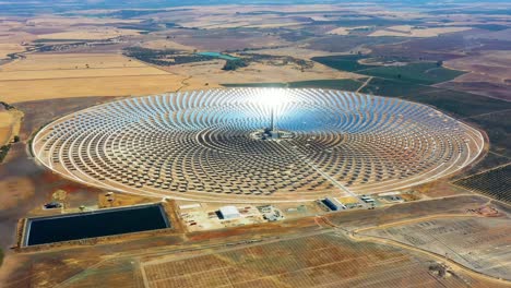 large circular power plant of solar panels in spain. there is the reflection of the sun in the the panels which produce renewable energy, solar energy - aerial view with a drone - environment concept