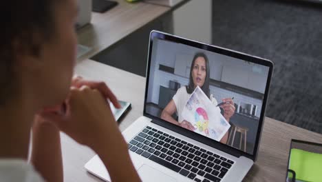 African-american-woman-having-a-video-call-on-laptop-with-female-colleague-at-office