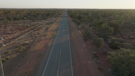 un clip de drone que muestra un camión de 4 carruajes conduciendo a lo largo de una larga carretera recta a través del interior de australia