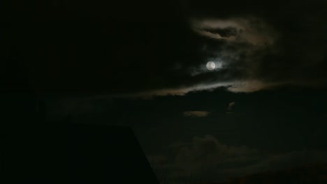 bright shining full moon in between clouds in east berlin, germany