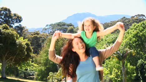 woman carrying her daughter on her shoulders