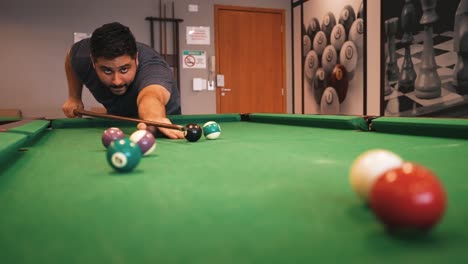 a man plays billiards hitting the white cue ball