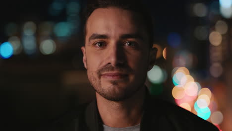 retrato atractivo joven hombre caucásico en el techo por la noche riendo feliz disfrutando de la vida nocturna urbana con luces de la ciudad bokeh en el fondo