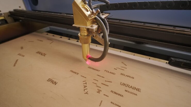 Cnc laser cutting machine cuts world map on wooden plank and plywood
