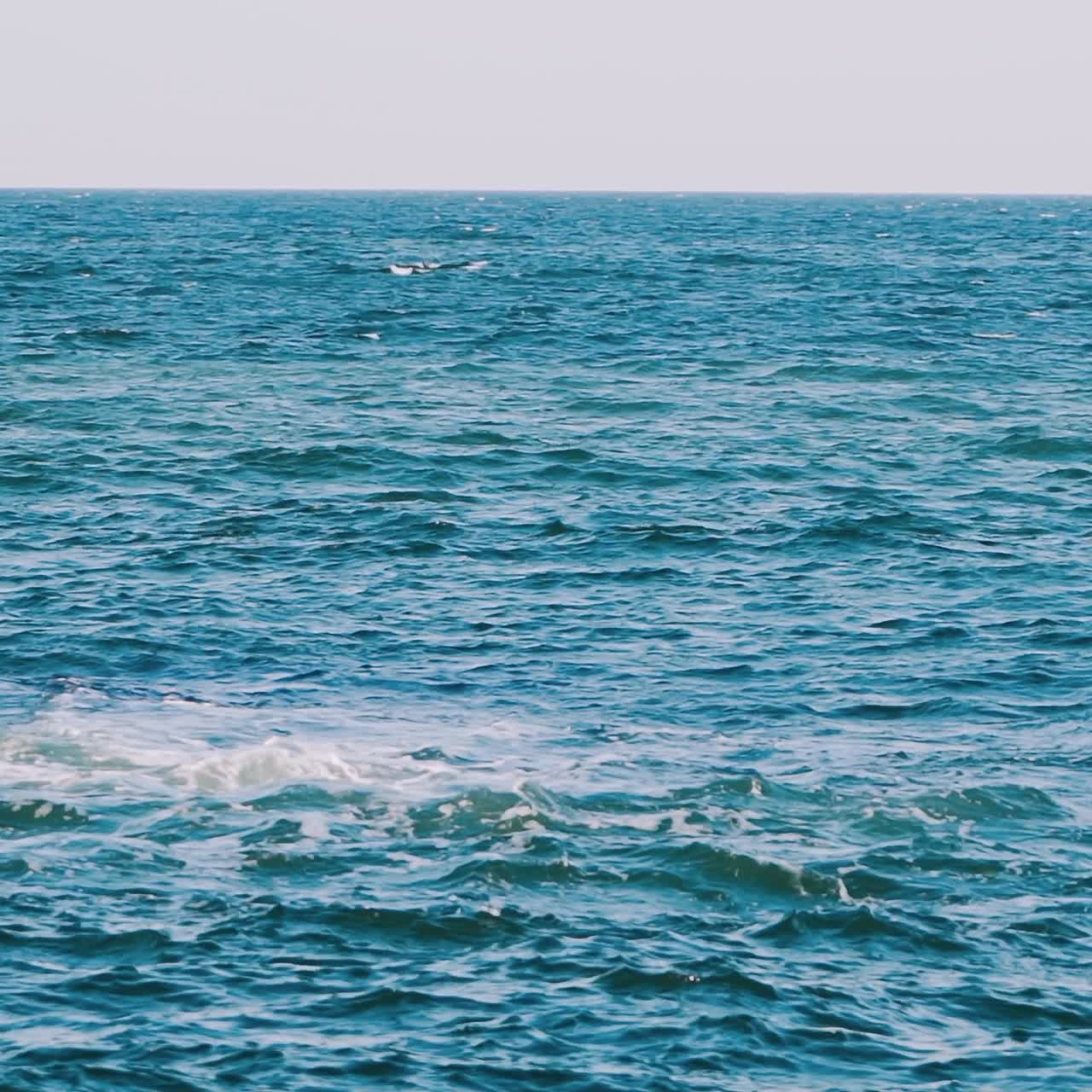 Waves swaying on the sea water. Amazing water background at storm. Beautiful blue water of the ocean with waves and white foam. Slow motion.