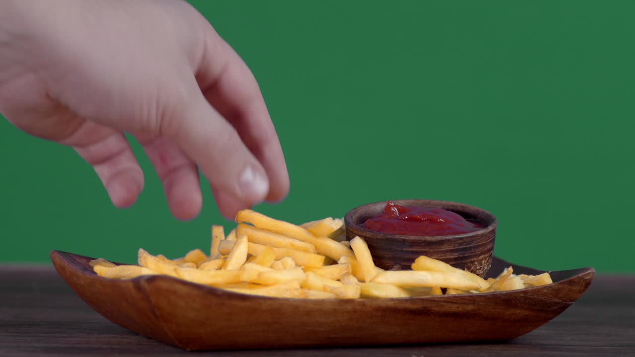Hand takes the chips and dips in tomato sauce.