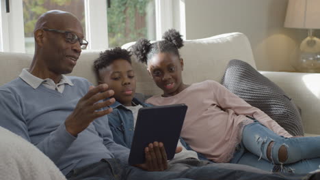 Grandfather-Reading-a-Story-to-His-Grandchildren-from-Electronic-Tablet