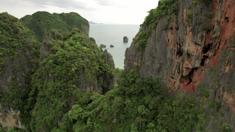 aerial view between the limestone rocks and tropical trees of railay overlooking phra nang cave beach, thailand