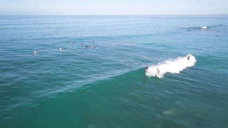 surfistas montando una ola en la playa de waikiki honolulu hawaii en un día de cielo azul, muñeca aérea