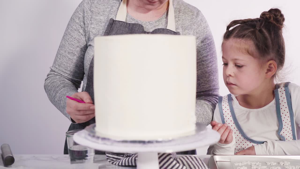 decorando el pastel funfetti redondo con copos de nieve de fondante rosado y blanco.