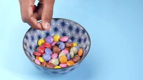 niño recogiendo dulces de varios colores en un cuenco de cerca