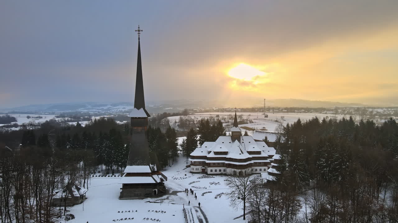 Luftdrone-utsikt over Peri-Sapanta-klosteret om vinteren, Romania. Hovedkirken og en bygning, besøkende, naken skog og snø rundt