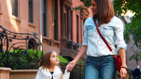 Madre-Con-Bolso-Rojo-Caminando-Por-La-Calle-Con-Su-Hija.