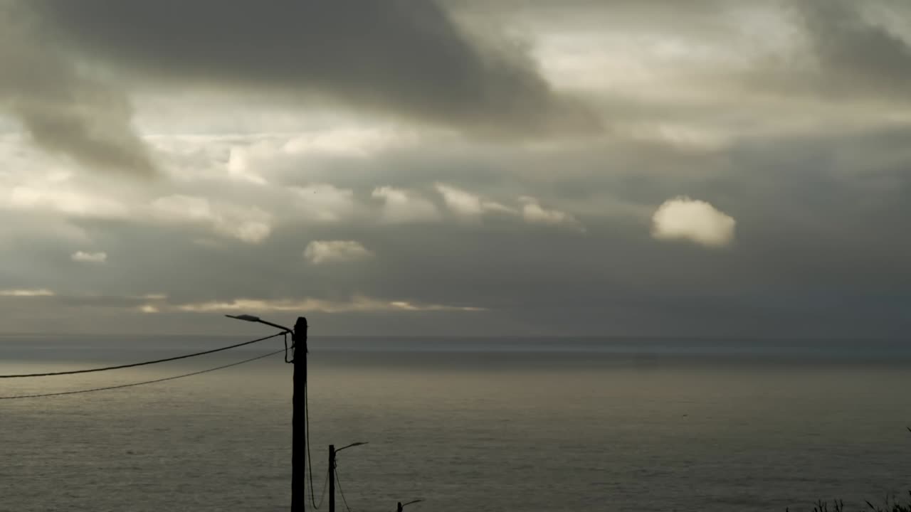 Grey storm clouds move rapidly over darkening coastal beach Timelapse
