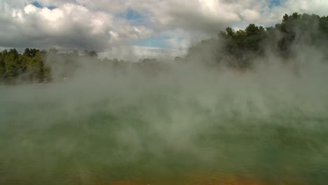 steam rises off a geothermal lake in new zealand's rotorua region