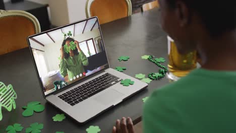 Lächelnde-Afroamerikanische-Frau-Mit-Kleeblattförmigen-Gegenständen-Bei-Einem-Videoanruf-Auf-Dem-Laptop