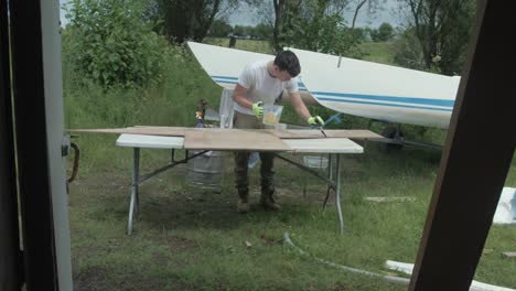 a young man coats a plywood sheet with epoxy resin