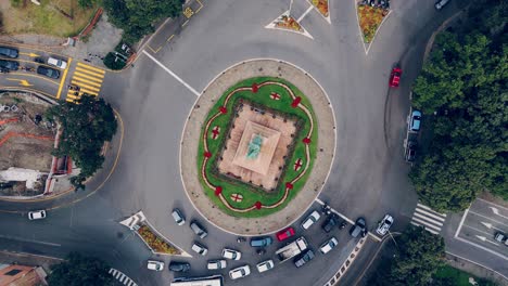 cars navigate a busy roundabout in genoa, italy, surrounded by greenery and city streets