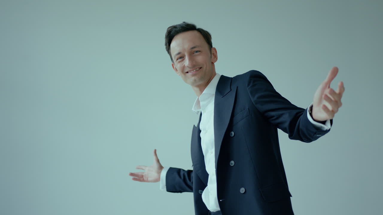 미소 짓는 어두운 머리 백인 남자가 양복을 입고 발에서 위로 기울어져 포즈를 취합니다.