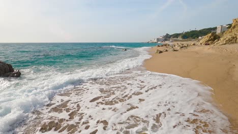 Hermosa-Playa-De-Arena-Mediterránea,-Maresme-Barcelona,-San-Pol-De-Mar,-Con-Rocas-Y-Mar-Tranquilo-Y-Turquesa,-Costa-Brava-Barcelona