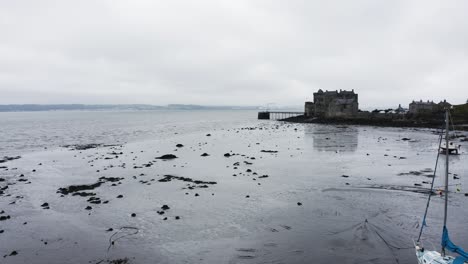 beached sailboats at low tide sitting in front of blackness castle in scotland