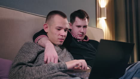 two men watching something on a laptop