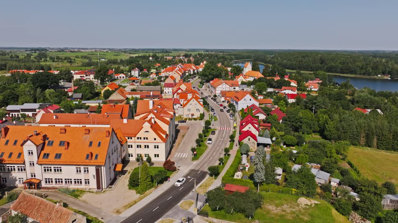 Vivid red rooftops and calm lake in warm daylight aerial scene of Wydminy Poland