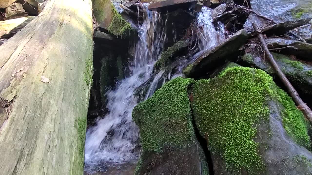 Closeup look at water in motion. Waterfall and big rocks in creek