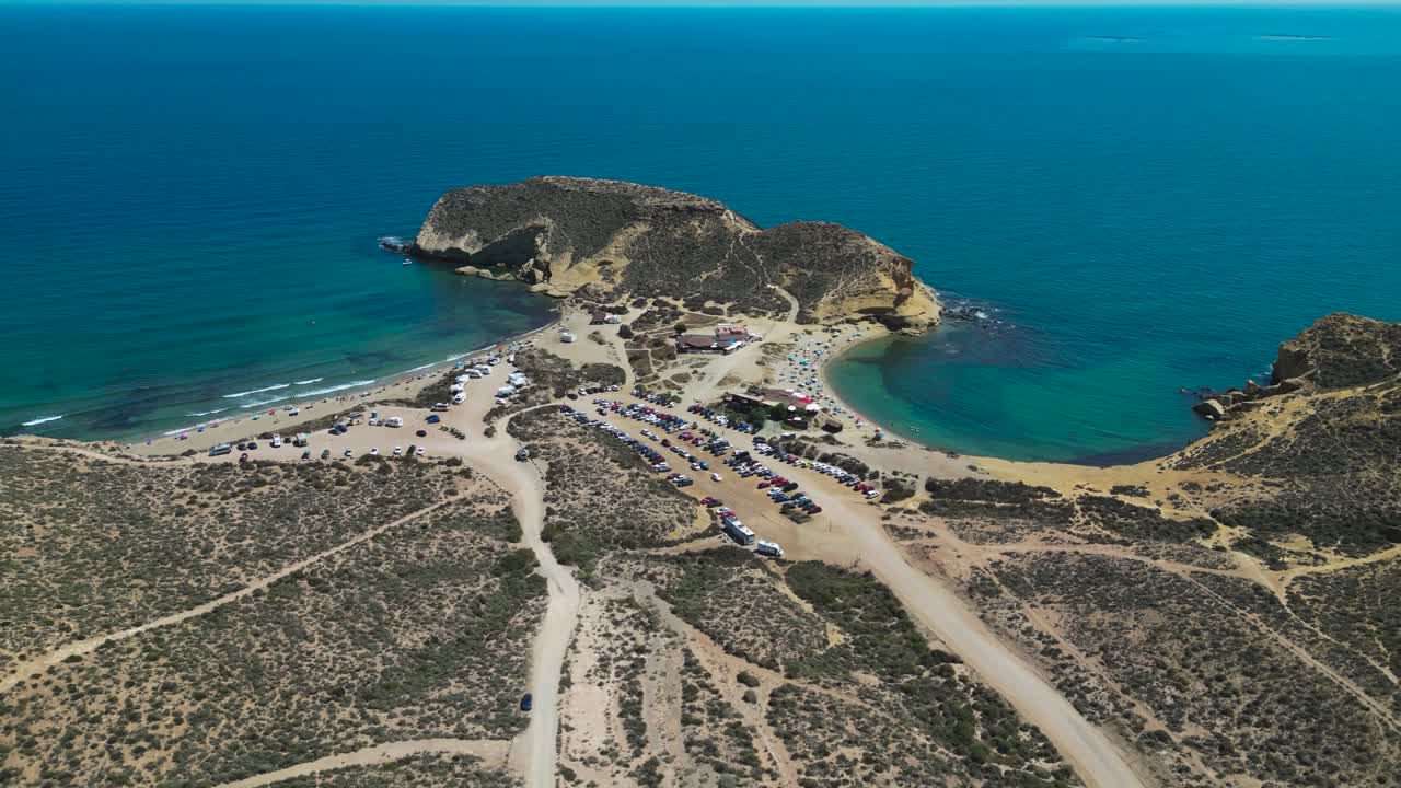 Aerial dolly reverse view of Playa la Carolina in Aguilas, Almeria. A paradise beach with blue turquoise water and white sand beach - Spain