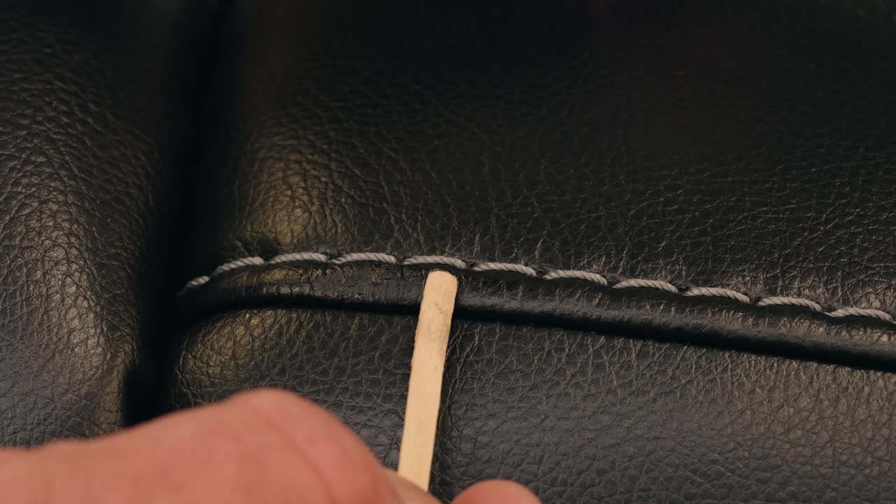 Hands paint then blend tiny scratch, making black leather surface look new