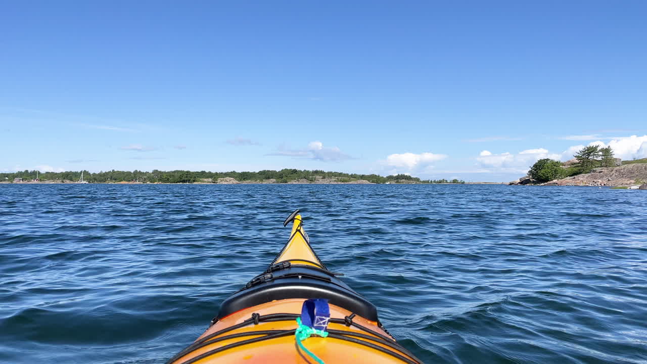 kayak amarillo de aguas abiertas flotando en el agua con una vista soleada del archipiélago en el fondo