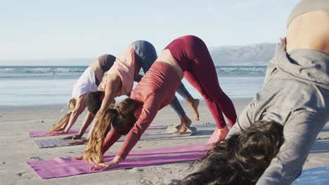 grupo de diversas amigas practicando yoga en la playa