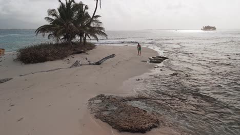 dron close shot from a young man walking along a beach of a remote island in san blas archipelago, panama