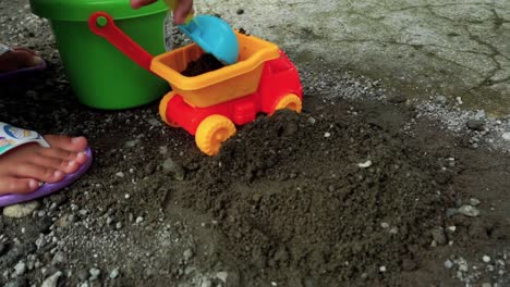 hand of children play with stone, truck toy and sand