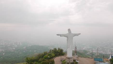 slow aerial flyover footage of the cristo rey statue that flies right past the head of the statue in the city of cali, colombia