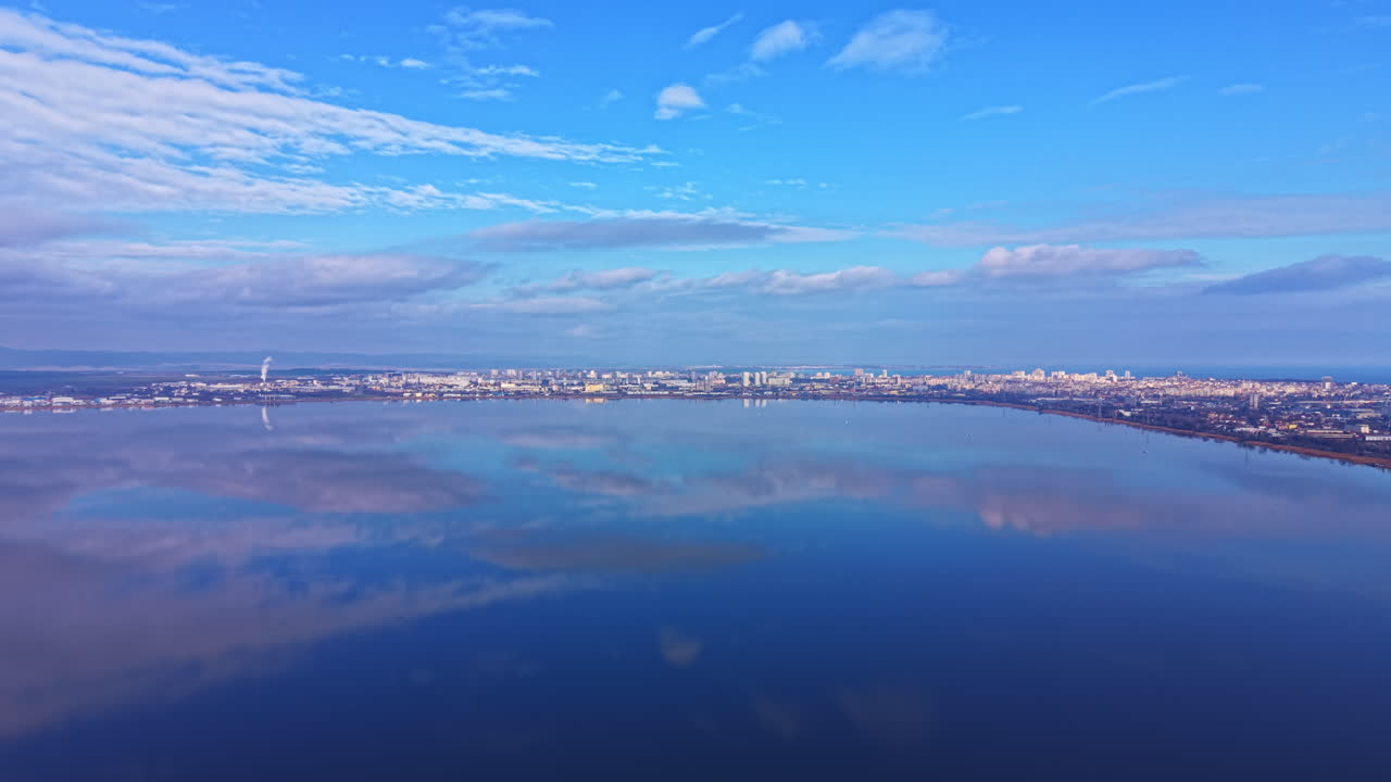 晴れた日の午後、青空に点在する雲の下、水面に映る都市のスカイラインの眺め