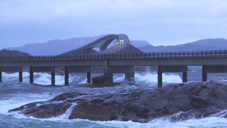 waves crashing upon rocks next to large bridge at the norwegian atlantic ocean coast.