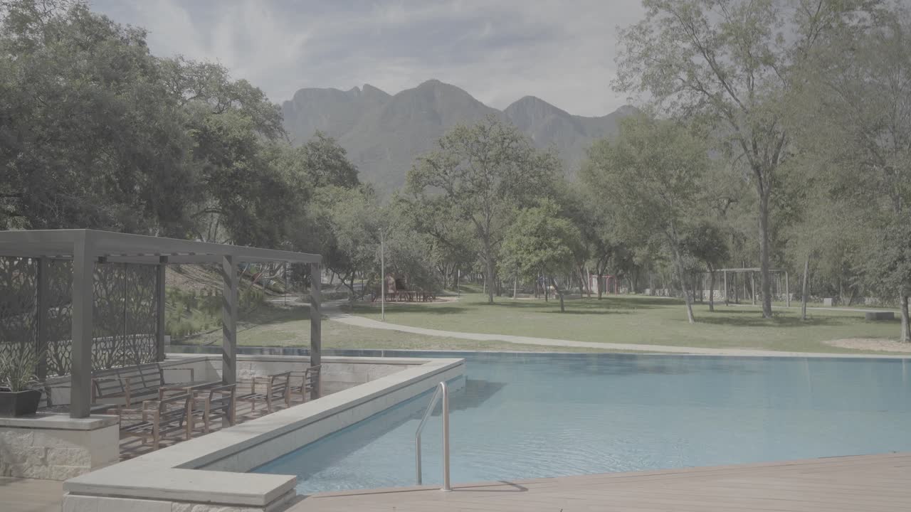 Lenta inquadratura di presentazione di una piscina privata con vista sulle montagne in estate.