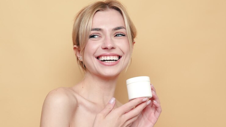 donna sorridente con un prodotto per la cura della pelle