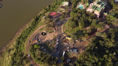 a dynamic orbital aerial footage of the public road going around the mansion surrounded by trees and some neighbor houses near the iguazu river at sunset