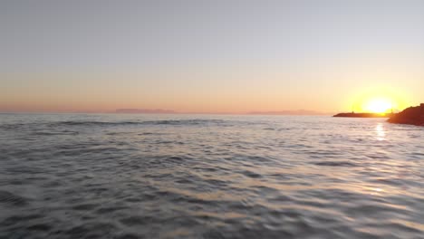 Ein-Blick-Auf-Den-Sonnenuntergang-Im-Hintergrund,-Der-Sich-Wie-Aus-Der-Sicht-Eines-Bootes-Rückwärts-über-Das-Meer-Bewegt
