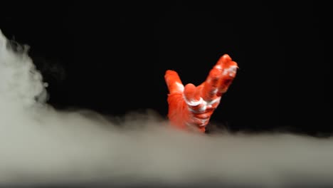 eerie red hand emerging from smoke on a dark background