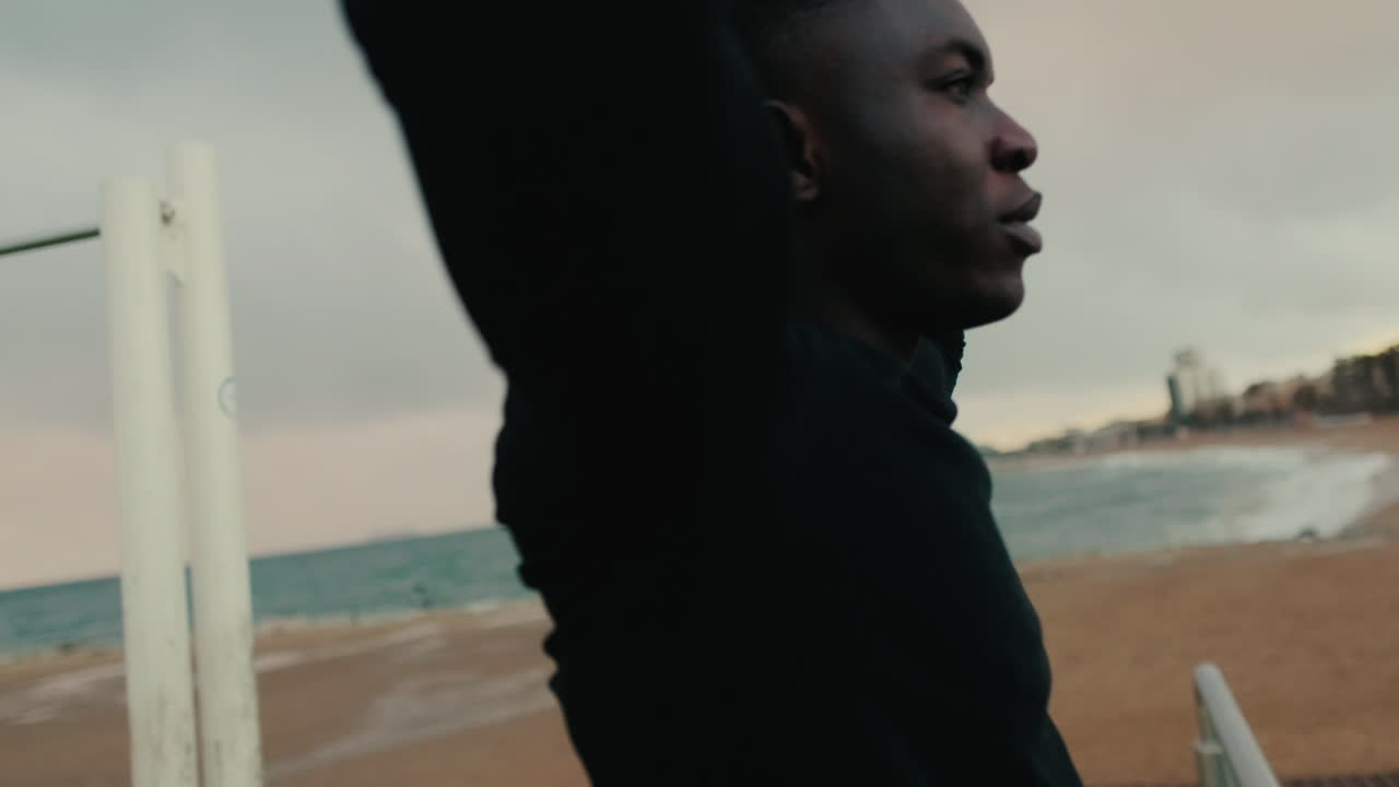 Young Black Man Stretching on a Beach Before Workout