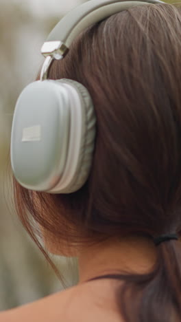 back view of young girl wearing headphones with a wristwatch on her hand, looking relaxed and connected with nature, capturing a peaceful moment while enjoying music outdoors