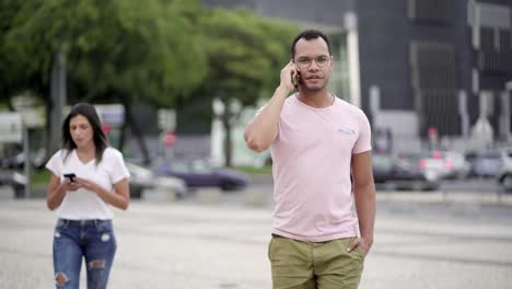 handsome man talking on phone while walking on street