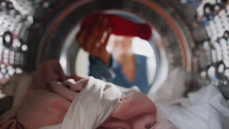 young woman taking out red sock mixed with white laundry from washing machine