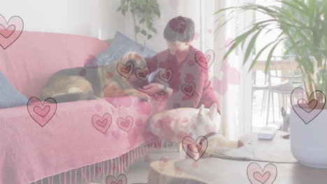 animation of heart emojis over happy caucasian woman with dogs