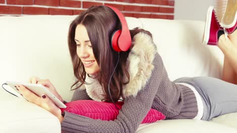 mujer sonriente con auriculares usando una tableta digital